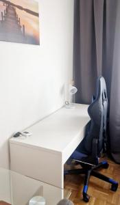 a white desk with a blue office chair next to a window at Cozy and beautiful flat in the centrum in Essen +4 photos