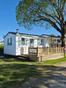 a white house with a fence and a tree at Camping Le Bellevue in Barzan