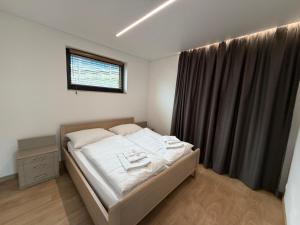a bedroom with a bed with white sheets and a window at MEANDER THERMAL & SKI REZORT ORAVICE in Oravice