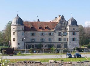 an old castle with two turrets and cars parked in front at Ferienwohnung N plus B in Mitwitz