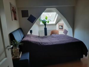 a bedroom with a purple bed and a window at Liroja's Vakantiehuis in Vlagtwedde