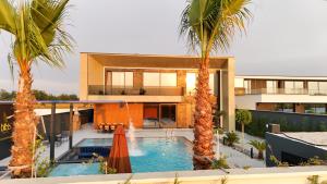 a house with a swimming pool and two palm trees at Bliss Luxury Villa in Rrushkull