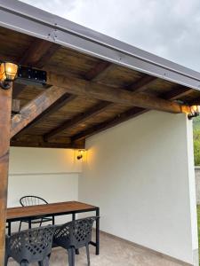 a patio with a wooden roof with a table and bench at Vikendica Casa Verde in Konjic