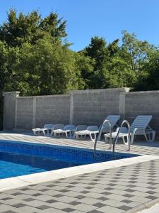 a swimming pool with blue chairs and a wall at Vikendica Casa Verde in Konjic