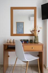 a desk with a white chair and a mirror at Flisvos in Sitia