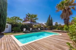 a swimming pool in a yard with a wooden deck at Villa 3 palmiers avec pisicne in Fréjus