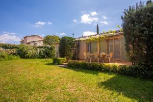 a garden with chairs and a house in the background at Villa 3 palmiers avec pisicne in Fréjus