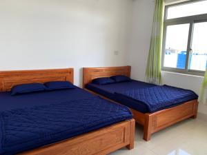 two beds with blue sheets in a bedroom with a window at Guest house Trung Hiếu in Rạch Giá