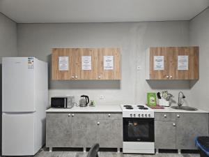 a kitchen with a white stove and a refrigerator at Qonaq Hostel in Astana