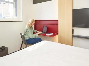 a woman sitting at a desk with a laptop at ibis budget Blankenberge in Blankenberge