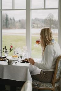 a woman sitting at a table with a glass of wine at Ööbikuoru Villa in Rõuge
