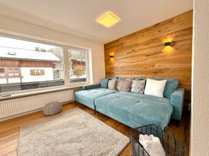 a living room with a blue couch and a window at Ferienhaus Alpenlodge in Oberstdorf