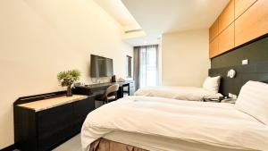 a bedroom with two beds and a desk and a tv at San Juan Easy Stay Inn Tainan in Tainan