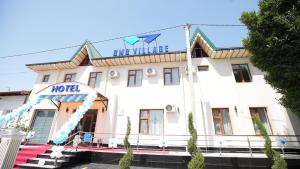 a hotel with a sign on the front of it at Bmb Village Jizzakh Hotel in Dzhailʼma