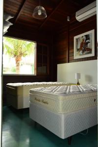 2 camas en una habitación con ventana en Casa De Madeira, en Bombinhas