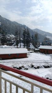a snow covered field with a fence and trees at Barot Palace in Barot  +12 photos