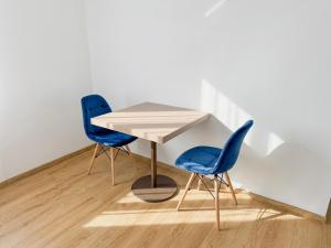 two blue chairs and a table in a room at Astral in Raszyn