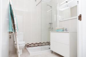 a white bathroom with a shower and a toilet at Apartamento en Cala'n Blanes in Ciutadella +16 photos