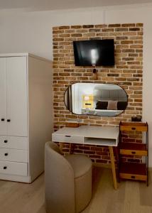 a living room with a tv on a brick wall at Summerscape Studios and Apartments in Corfu