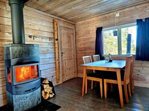 a fireplace in a log cabin with a table and a stove at Aurora Camp Kiruna in Kiruna