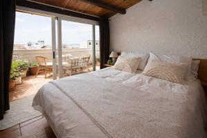 a bedroom with a large white bed and a balcony at Seafront Iconic Lighthouse View Punta Secca in Punta Secca