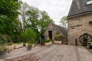 an outdoor deck with a stone building and a building at Le Moulin De Lesnevé in Saint-Avé