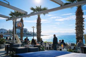 people sitting at tables in a restaurant near the ocean at Begonville Villas Ladies Beach in Kuşadası