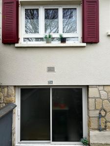 a building with two windows and two potted plants at Pause confortable, escapade culturelle in Caen
