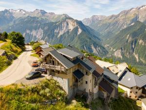 a house on a hill with mountains in the background at Chalet Le Perchoir, Spa, Sauna, sur les pistes in Villard-Reculas