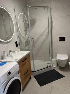 a bathroom with a shower and a washing machine at Apartament Umami in Pniewy