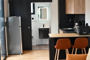 a kitchen with a refrigerator and a counter with chairs at Lilikaz in Saint-Laurent-de-la-Prée