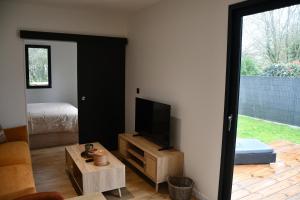 a living room with a television and a bedroom at Lilikaz in Saint-Laurent-de-la-Prée