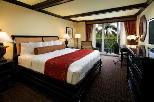 a hotel room with a bed and a desk and a window at Jupiter Beach Resort & Spa in Jupiter