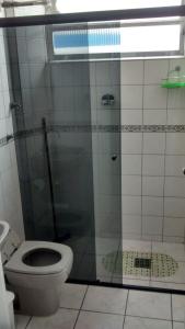 a bathroom with a glass shower with a toilet at Mares do Sul Apartment in Praia Grande