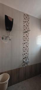 a bathroom with a toilet and a television on the wall at 2 BHK All AC Rooms Solapur Home Stay By Stay Nestura in Solapur +33 photos
