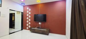 a living room with a tv on a wall at 2 BHK All AC Rooms Solapur Home Stay By Stay Nestura in Solapur