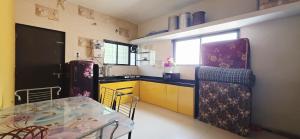 a kitchen with a table and yellow cabinets and a refrigerator at 2 BHK All AC Rooms Solapur Home Stay By Stay Nestura in Solapur