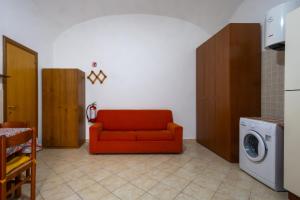a living room with a red couch and a washing machine at Dimora Dina Guglionesi in Guglionesi
