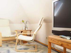 a living room with a chair and a tv at Gaestehaus-W-13 in Prerow