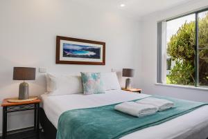 a bedroom with a large white bed with a window at Surfside Ocean Beach Denmark Holiday Accommodation in Denmark