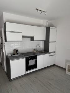 a white kitchen with white cabinets and a sink at Apartament Helsinki in Pniewy
