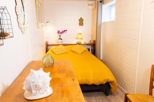 a bedroom with a yellow bed and a wooden table at Les Colombes in Saint-Tricat