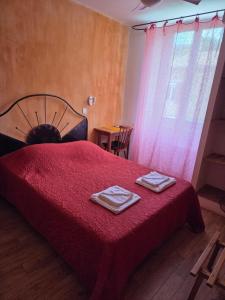 a bedroom with a red bed with two towels on it at Hotel Des Sites in Salavas
