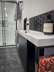a bathroom with a sink with a bottle of soap on it at Guesthouse on Gardiners in Christchurch +7 photos