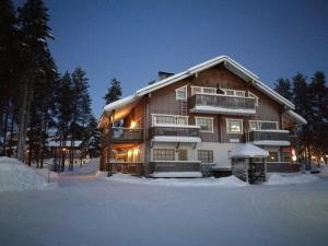 une grande maison en bois dans la neige la nuit dans l'établissement Levin Alppi 3 A 1 Apartment, à Levi