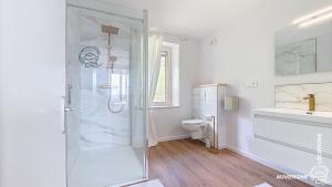 a white bathroom with a shower and a toilet at Aux Marches du Château in Murol +15 photos