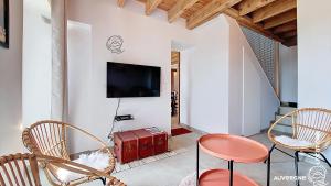 a living room with chairs and a tv on the wall at Aux Marches du Château in Murol