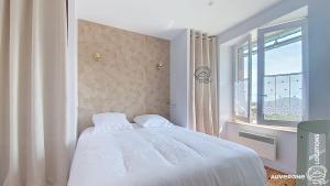 a bedroom with a white bed and a window at Aux Marches du Château in Murol
