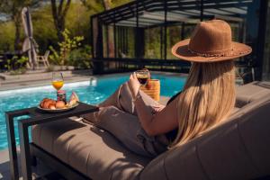 a woman in a hat sitting on a couch next to a pool at Vakantierijk Waarland in Waarland