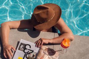 a woman in a hat sitting at a table next to a pool at Vakantierijk Waarland in Waarland